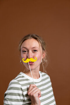 Woman with mustache prop over brown background