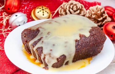Traditional South African Malva pudding with creamy custard on rustic Christmas table. A favorite dessert all year round.