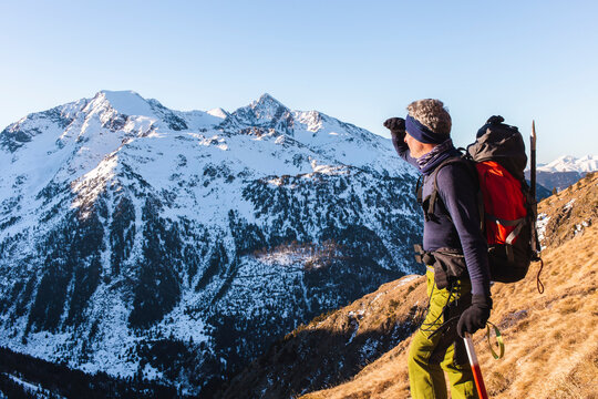 Man carrying backpack hiking with pole on mountain in winter
