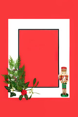Christmas nutcracker ornament and winter greenery fauna background on red with white frame. Merry Christmas Noel Yule greeting card, gift tag, letter, menu, invitation.