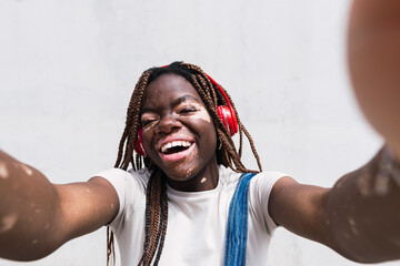 Happy woman taking selfie in front of white wall