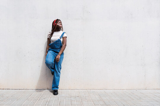 Thoughtful young woman leaning on white wall
