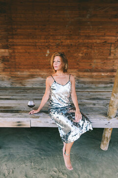 Thoughtful woman with wineglass sitting on wooden veranda