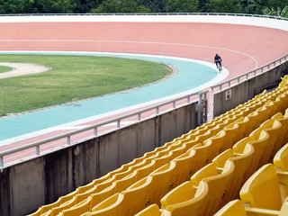 Tuinposter cyclists practicing cycling in bicycle race track with vacant stadium seats © andy0man