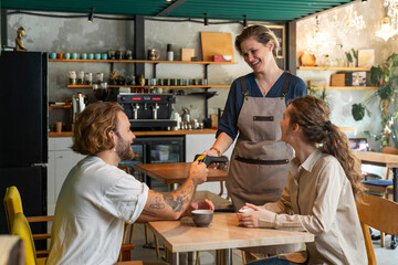 Customers paying through credit card sitting at cafe