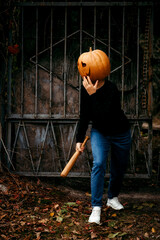 A girl in a Halloween pumpkin holds a bat in her hands and scares people