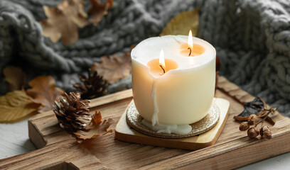 Autumn still life with a burning candle, leaves and a knitted element.