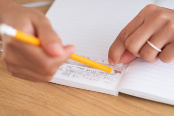 High angle of crop anonymous female emphasizing important notes with ruler and pencil in planner on wooden table during work in office