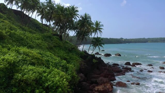 Capture the mesmerizing beauty of Goa's tree-lined beach with its crystal-clear blue waters and rhythmic waves in this stunning drone video. Experience the serene and picturesque coastal charm of this