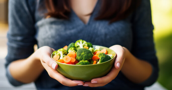 Woman holding Buddha bowl with salad, broccoli, greens, carrots, tomatoes, peppers, sprouts in hands. Healthy vegan food, clean eating, dieting, top view