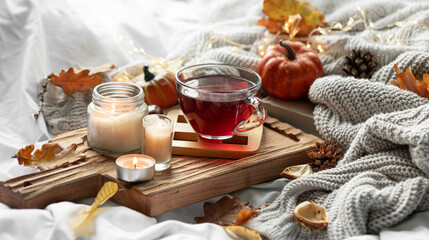 Autumn composition with a cup of tea, leaves and a knitted element.
