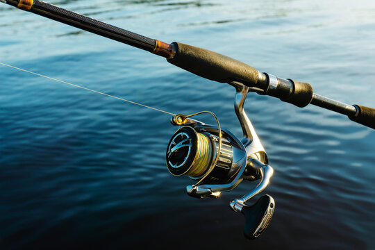 Spinning And Branded Shimano Reel On The Background Of The Water Surface. Professional Tackle For Catching Predatory Fish. Close Up. Nizhny Novgorod, Russia - September 28, 2021