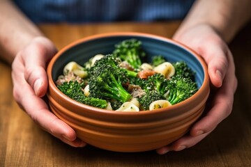 hand holding a bowl of orecchiette with broccoli rabe - obrazy, fototapety, plakaty