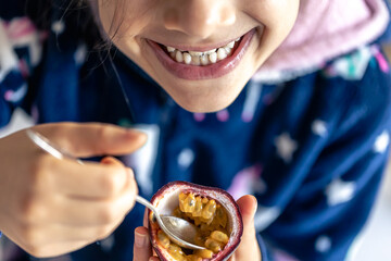 Little girl eats passion fruit, mouth close-up.