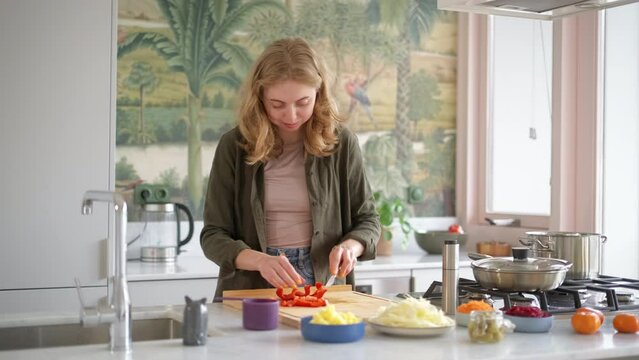 Portrait of young woman preparing vegetable meal. Happy smiling female cutting sweet pepper paprika for soup. Fresh vegetables for vegan health dish. Food Delivery Services Concept. stress relief