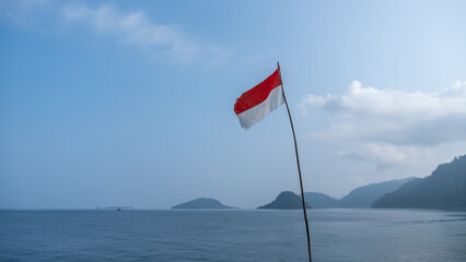 the flag of the republic of indonesia or monaco is flying with the sea and island in the background
