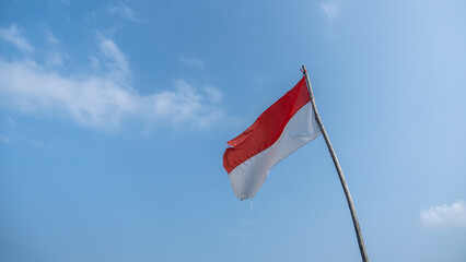 Moroccan or Indonesian flag flying against a bright blue sky background