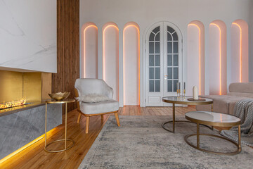 cozy interior of a modern living room with a fireplace, decorative panels and LED lighting with...