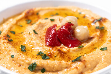 Roasted red pepper hummus in white bowl isolated on white background. Close up
