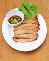 Grilled pork, Roasted pork neck with spicy sour dipping sauce in white plate on wood background.