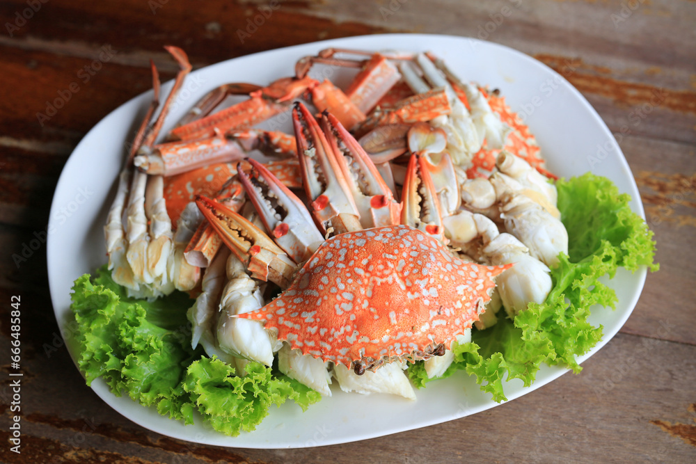 Poster steamed blue crab or horse crab on white plat against wood background. top view.