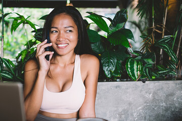 Beautiful young woman calling friend using mobile in cafe