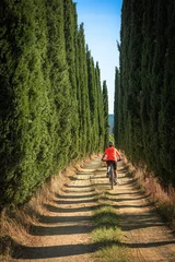 Papier Peint photo autocollant Toscane nice senior woman riding her electric mountain bike in a cypress avenue in the Ghianti Area of Tuscany,Italy