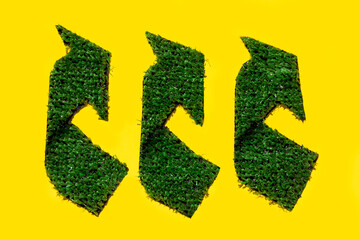 A green recycle sign made out of grass