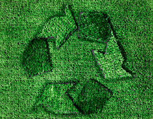 A green recycle sign made out of grass