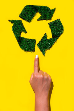 A hand pointing to a green recycle sign