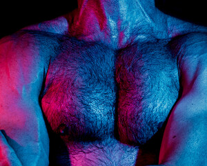 Strong man with muscular hairy chest in neon lights