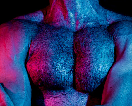 Strong man with muscular hairy chest in neon lights