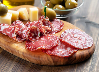 Obraz premium Salamit with cheese and olives on a wooden board, tapas