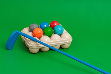 Set of colorful golf balls in box with golf club