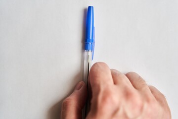 Blue plastic pen in hand of young man on white background. High-quality photo