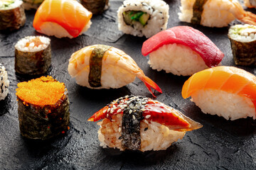 Sushi. An assortment of rolls, maki, nigiri etc on a black background. Japanese restaurant