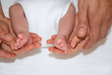Obraz na płótnie Canvas Baby feet in mother and father hands. Parents and her Child. Happy Family concept. Beautiful conceptual image of child care and happy childhood