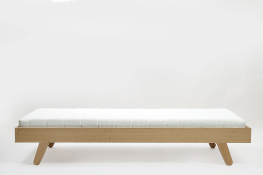 Studio shot of wooden single bed with mattress on white background