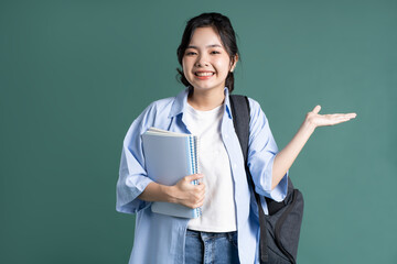 Portrait of a beautiful Asian student on a green background