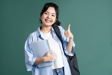 Portrait of a beautiful Asian student on a green background