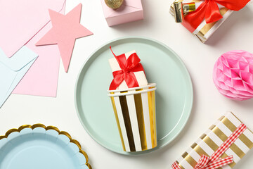 Gift boxes, paper cups and plates on light background, top view