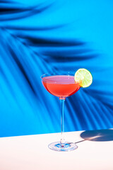 Siesta cocktail drink with tequila, grapefruit and lime juice, syrup and red bitter, liqueur. Blue background, hard light and shadows