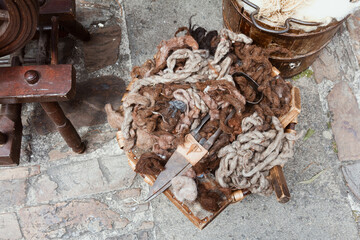 Vintage spinning wheel and raw wool on stone ground