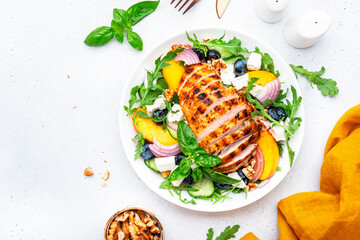 Tasty salad with peaches, grilled chicken breast, blueberries, red onion, feta cheese, basil and...
