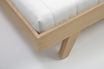 Studio shot of wooden single bed with mattress on white background