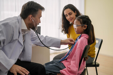 Male doctor using stethoscope to check up health children in examination hospital room. Pediatrician doctor talking to kids with parent in medical clinic. Healthcare and medical Kids concept.