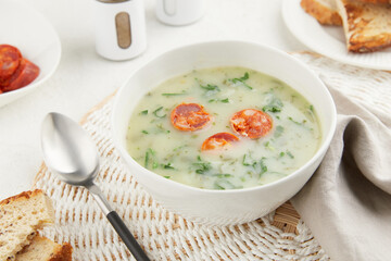 Typical Portuguese soup Caldo Verde with bread and chorizo sausage on gray background