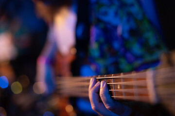 Bass guitar player or guitarist playing music instrument (focus on hand)