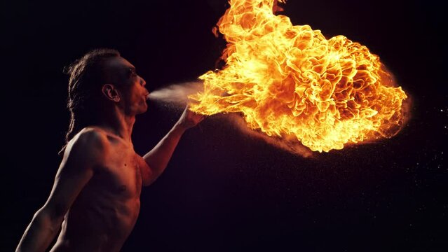 Creative Super Slow Motion Footage. Fire Performer Breathing Out Fire Like a Dragon at a Carnival. Portrait of a Topless Male Fire Artist Making a Live Show with Practical Effects