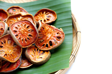 Dried bael fruit slices on banana leaf in bamboo weave plate